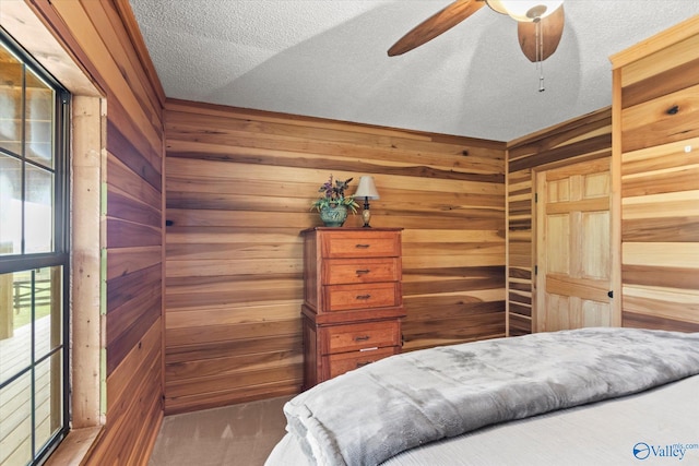 bedroom featuring lofted ceiling, a textured ceiling, ceiling fan, and wooden walls