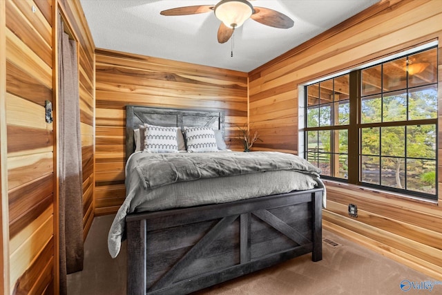 carpeted bedroom featuring ceiling fan, wood walls, and a textured ceiling