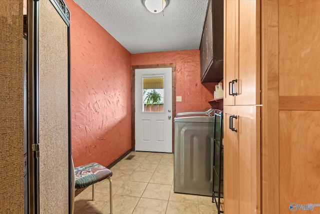washroom with cabinets, washer / dryer, a textured ceiling, and light tile patterned floors
