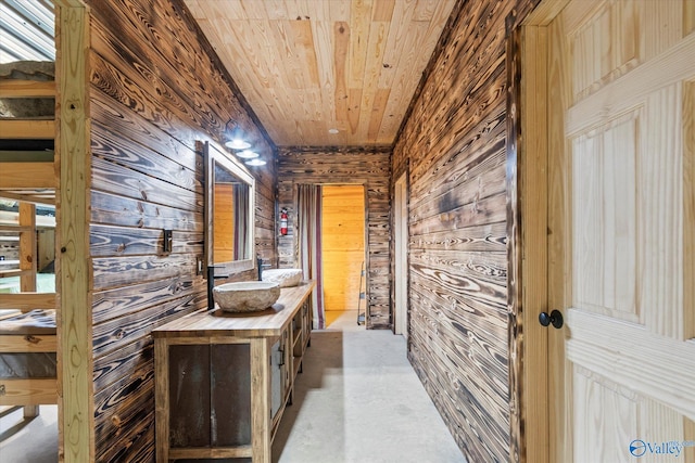 corridor with wooden ceiling, wooden walls, and sink
