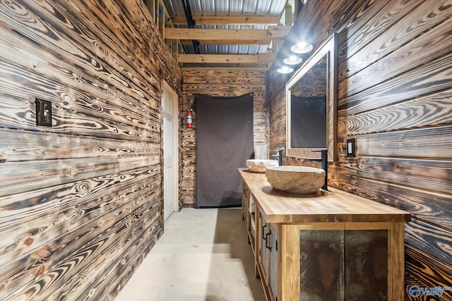 bathroom with vanity, concrete floors, and wood walls