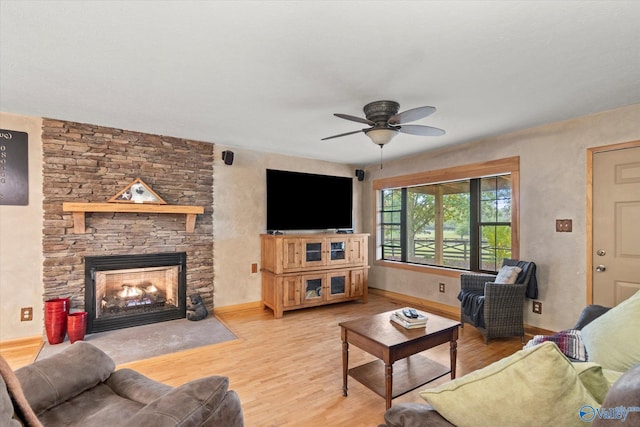 living room featuring ceiling fan, a fireplace, and light hardwood / wood-style flooring