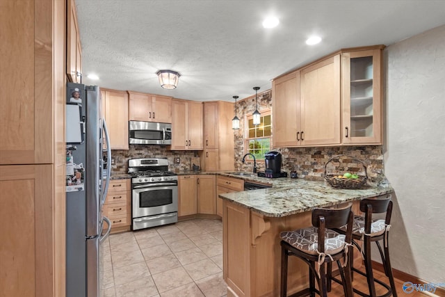 kitchen with pendant lighting, light brown cabinetry, stone countertops, kitchen peninsula, and stainless steel appliances