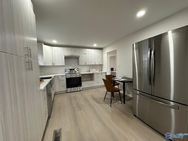 kitchen with sink, white cabinetry, stainless steel appliances, tasteful backsplash, and light hardwood / wood-style floors