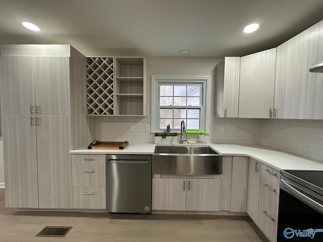 kitchen with dishwasher, sink, backsplash, and light hardwood / wood-style flooring