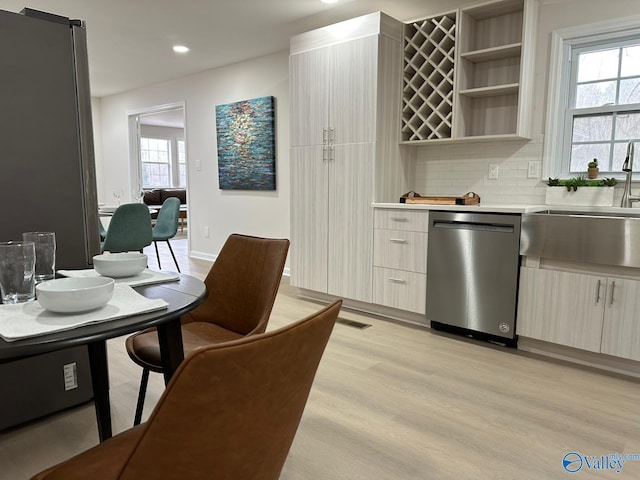 kitchen featuring appliances with stainless steel finishes, sink, backsplash, and light hardwood / wood-style flooring