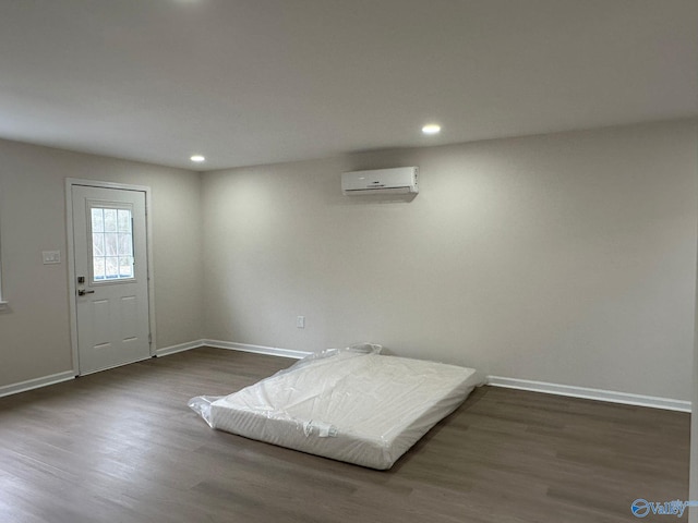 bedroom with dark hardwood / wood-style flooring and an AC wall unit