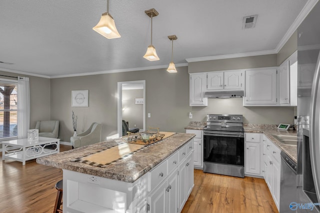 kitchen with decorative light fixtures, stainless steel appliances, a kitchen island, and white cabinetry