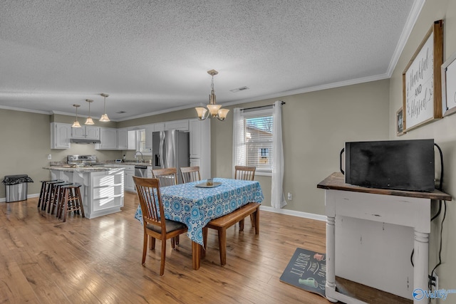 dining area featuring light hardwood / wood-style floors, an inviting chandelier, crown molding, and sink