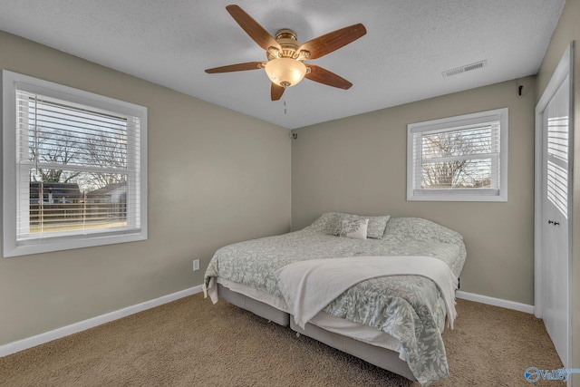 carpeted bedroom with ceiling fan and a textured ceiling