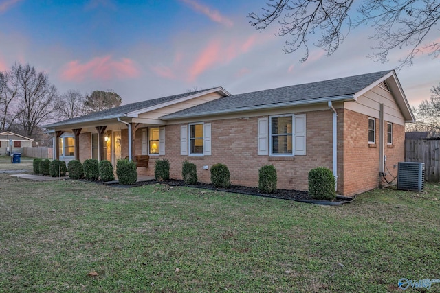 single story home with a porch, central AC unit, and a lawn