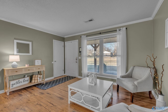 living area with a textured ceiling, light wood-type flooring, and crown molding