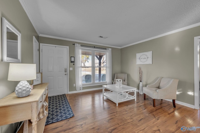 living area featuring crown molding, a textured ceiling, and hardwood / wood-style flooring