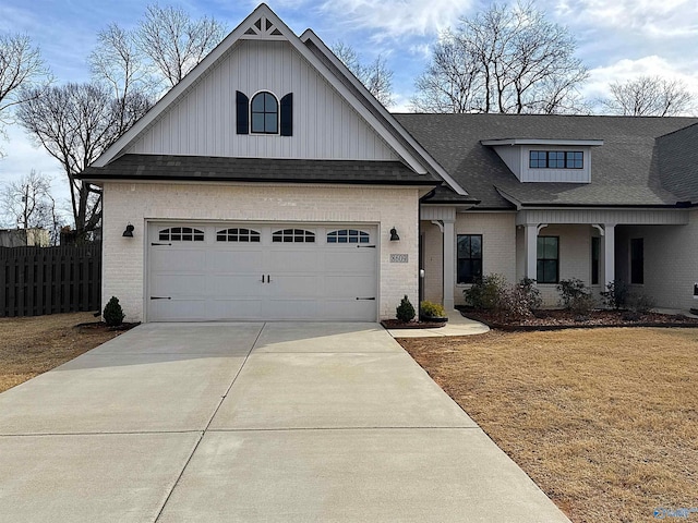 view of front of property featuring driveway, brick siding, roof with shingles, and fence