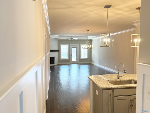 kitchen featuring dark wood-style floors, a fireplace, ornamental molding, open floor plan, and a sink