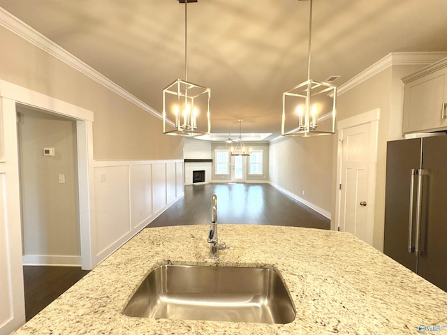 kitchen with a sink, a notable chandelier, crown molding, and high end fridge