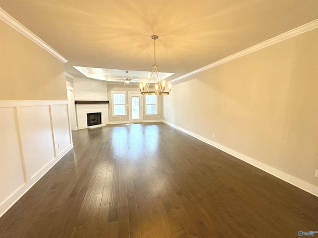 unfurnished living room with a notable chandelier, a fireplace, crown molding, and dark wood-type flooring