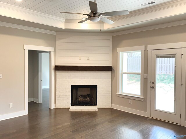 unfurnished living room featuring dark wood-style flooring, visible vents, baseboards, a tray ceiling, and crown molding