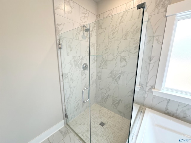 bathroom featuring marble finish floor, a shower stall, a wealth of natural light, and baseboards