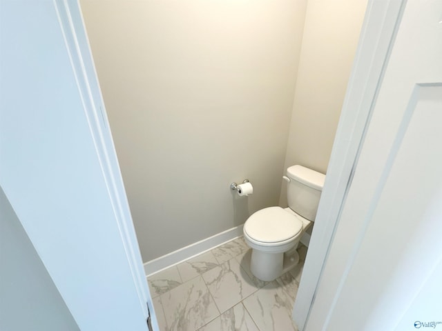 bathroom featuring toilet, marble finish floor, and baseboards