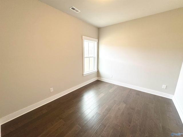 unfurnished room with dark wood finished floors, visible vents, and baseboards