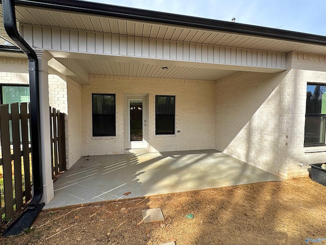 entrance to property featuring brick siding and a patio