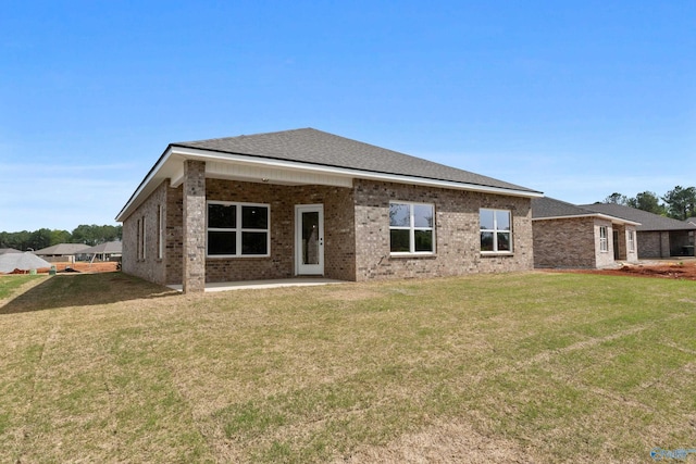 back of house with brick siding, a yard, and a patio area