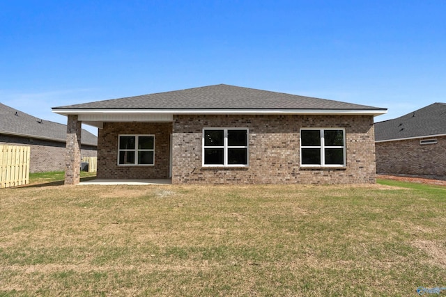 back of property with a yard, fence, a patio area, and brick siding