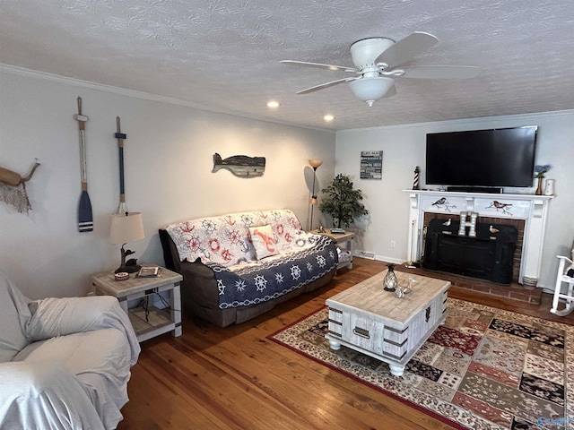 living room featuring crown molding, a brick fireplace, a textured ceiling, ceiling fan, and hardwood / wood-style floors