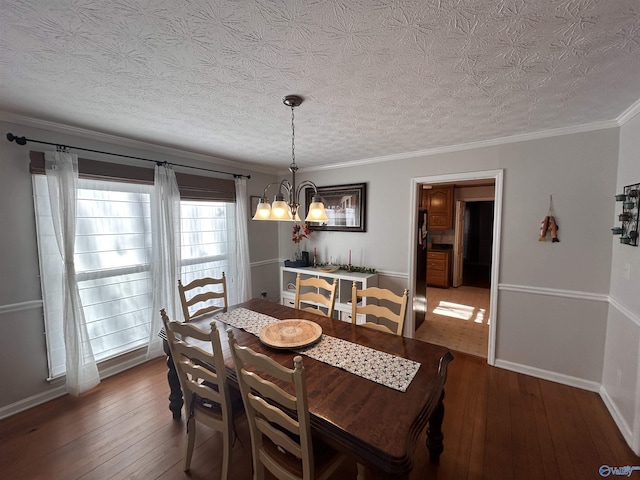 dining room featuring a notable chandelier, dark wood-type flooring, ornamental molding, and a textured ceiling