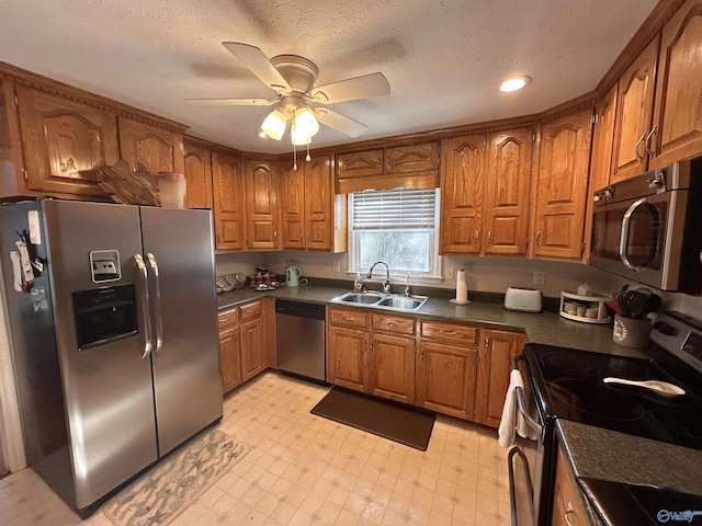 kitchen with sink, stainless steel appliances, a textured ceiling, and ceiling fan