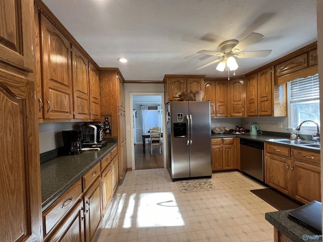 kitchen featuring sink, ceiling fan, stainless steel appliances, ornamental molding, and a textured ceiling