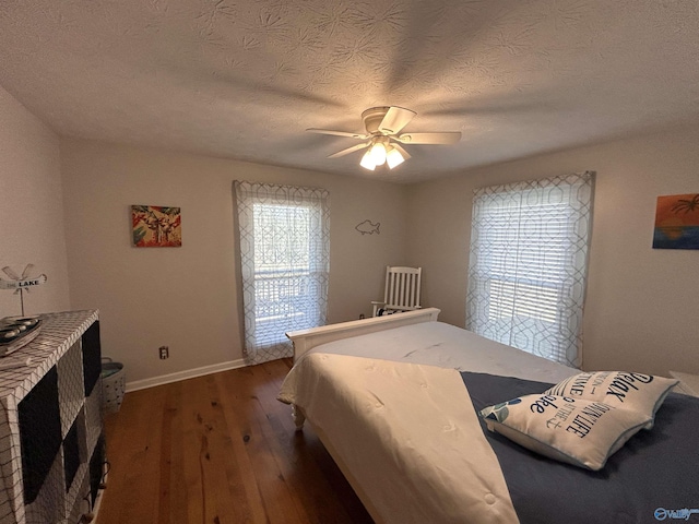 bedroom featuring ceiling fan, dark hardwood / wood-style flooring, and a textured ceiling