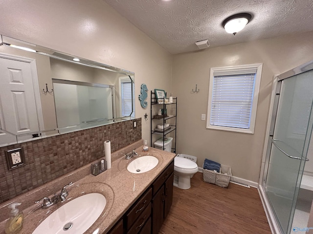 bathroom with tasteful backsplash, hardwood / wood-style flooring, vanity, an enclosed shower, and a textured ceiling