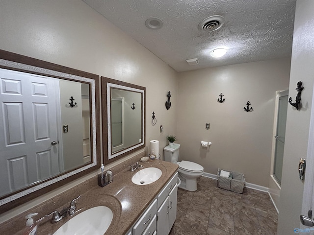 bathroom featuring a shower with door, vanity, a textured ceiling, and toilet