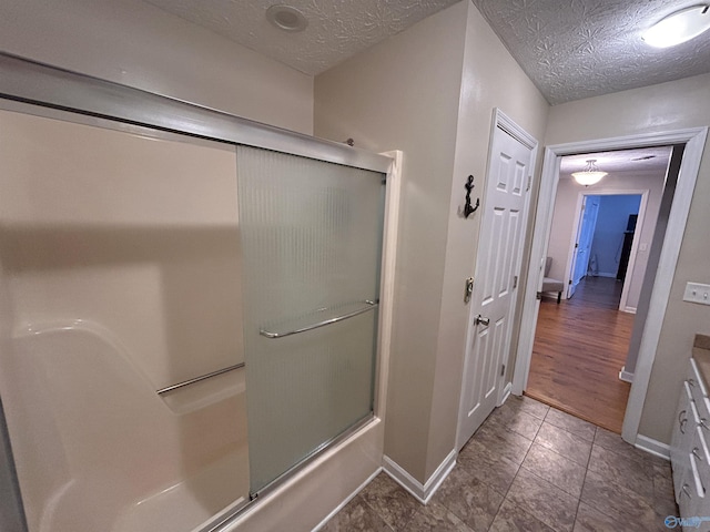 bathroom with vanity, enclosed tub / shower combo, and a textured ceiling