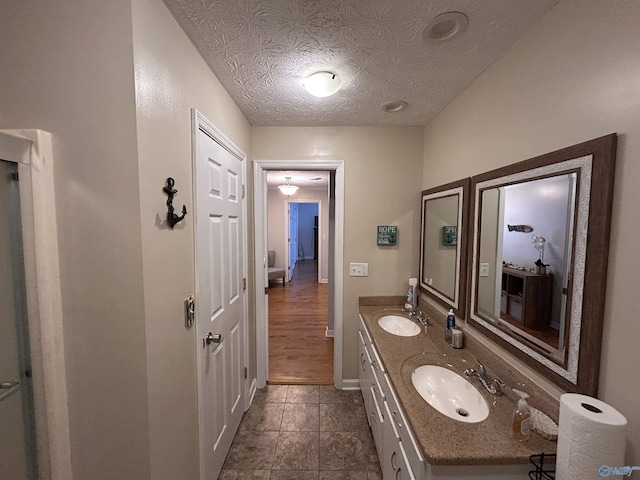 bathroom with tile patterned flooring, vanity, and a textured ceiling