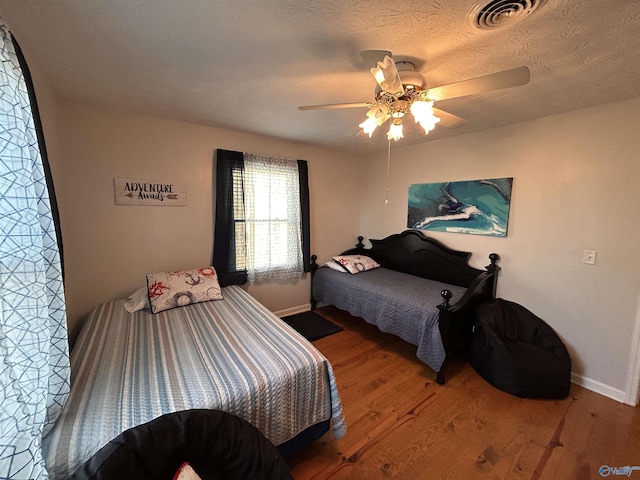 bedroom with wood-type flooring, a textured ceiling, and ceiling fan