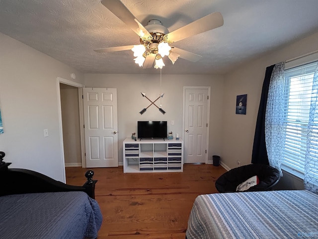 bedroom featuring dark hardwood / wood-style flooring, ceiling fan, and a textured ceiling