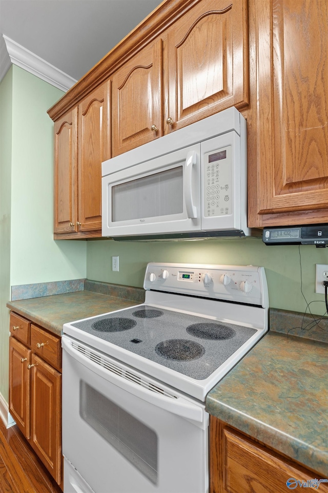 kitchen featuring white appliances, brown cabinets, crown molding, and dark wood-style flooring