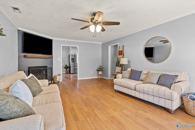 living room with hardwood / wood-style flooring, ceiling fan, ornamental molding, and a textured ceiling