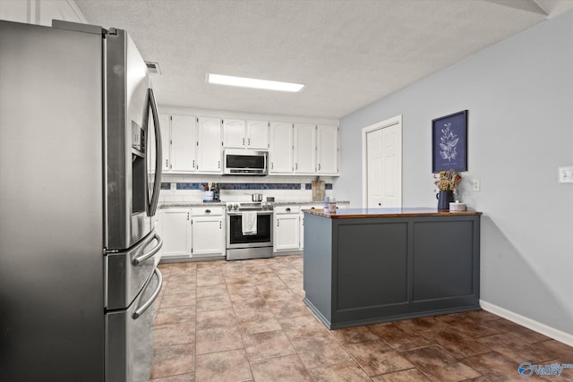 kitchen featuring white cabinets, appliances with stainless steel finishes, backsplash, and a textured ceiling