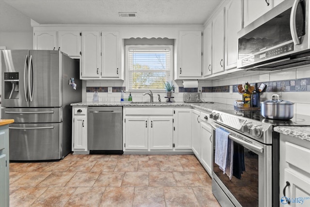 kitchen featuring white cabinets, stainless steel appliances, tasteful backsplash, and sink