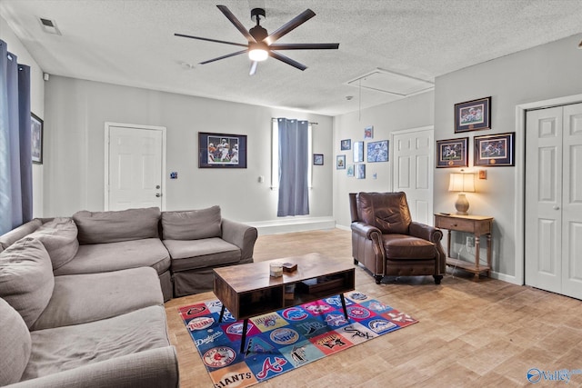 living room featuring ceiling fan, a textured ceiling, and light hardwood / wood-style flooring