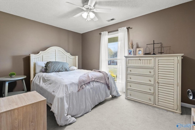 bedroom with ceiling fan, light carpet, and a textured ceiling