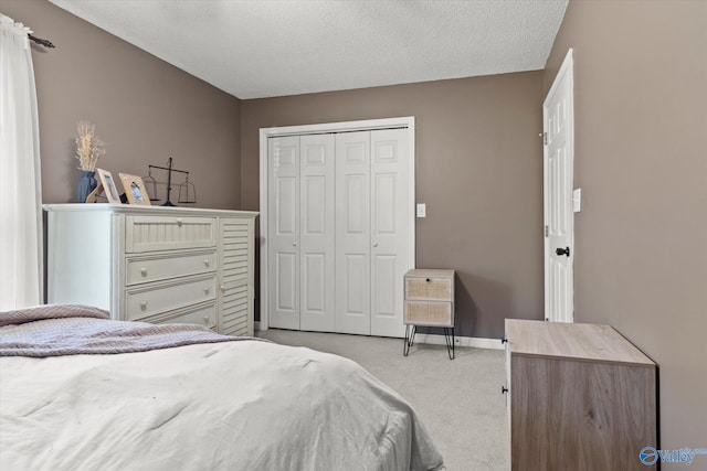 bedroom featuring light carpet, a closet, and a textured ceiling