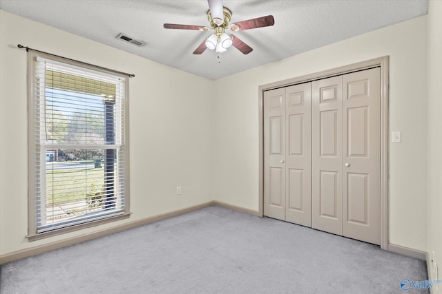 unfurnished bedroom with multiple windows, ceiling fan, and a textured ceiling