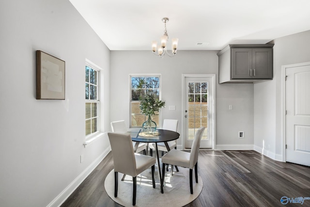 dining space featuring dark wood-style flooring, a notable chandelier, and baseboards