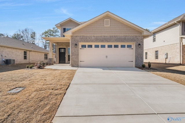 view of front facade featuring a garage, concrete driveway, brick siding, and central air condition unit