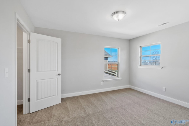 carpeted spare room featuring baseboards and visible vents